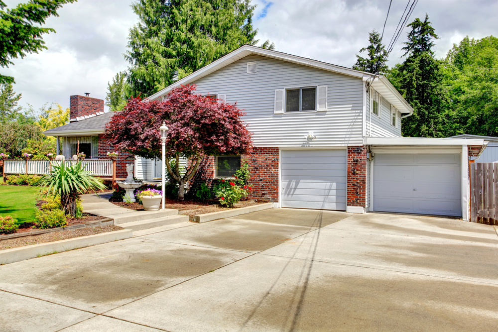 House exterior with brick wall trim, garage and spacious concrete floor driveway - Big Easy Paver Patios